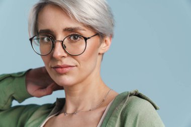 Beyaz tenli güzel gümüş kız mavi arka planda gözlüklü poz veriyor.