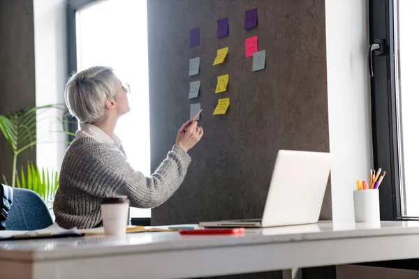 Weißhaarige Fokussierte Frau Arbeitet Büro Mit Notizen Und Laptop — Stockfoto