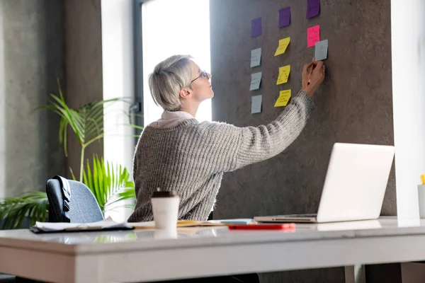 Weißhaarige Fokussierte Frau Arbeitet Büro Mit Notizen Und Laptop — Stockfoto