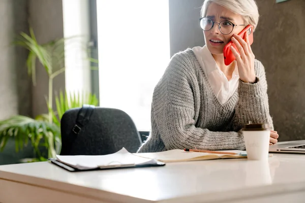 White Haired Brooding Woman Talking Mobile Phone While Working Laptop — Stock Photo, Image