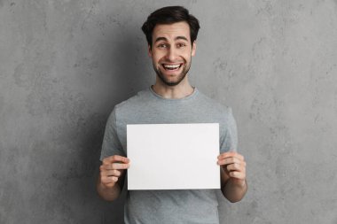 Gri üzerine izole edilmiş beyaz tahtası olan yakışıklı genç bir adam.