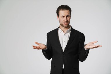 Tıraşsız, hoşnutsuz, el kol hareketi yapan ve beyaz arka planda izole edilmiş kameraya bakan adam.