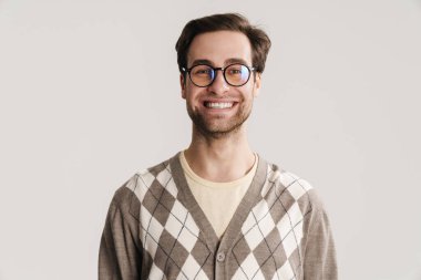 Neşeli yakışıklı adam gülümsüyor ve beyaz arka planda izole edilmiş kameraya bakıyor.