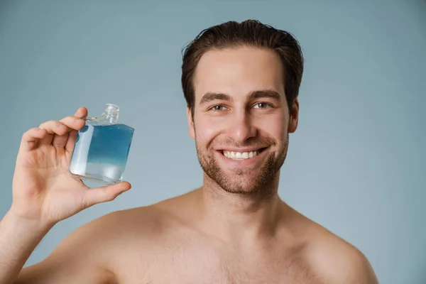 Shirtless White Man Smiling While Showing Cologne Isolated Blue Wall — Stock Photo, Image