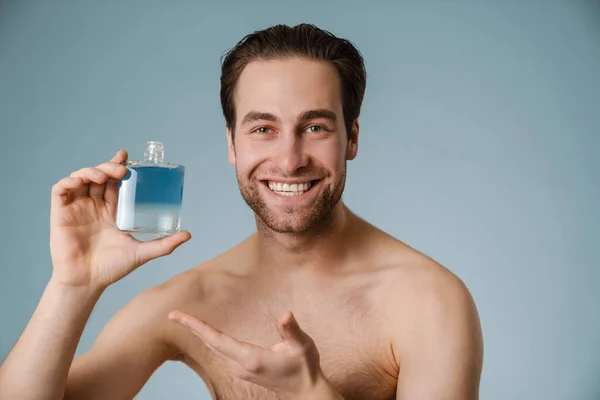 Biały Człowiek Bez Koszuli Uśmiecha Się Pokazując Wodę Kolońską Odizolowaną — Zdjęcie stockowe