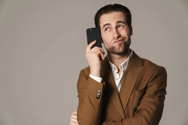Нездоланний Спантеличений Чоловік Дивиться Вгору Позує Мобільним Телефоном Ізольовано Сірому — стокове фото