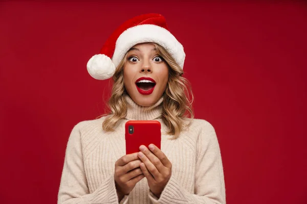 Glad Söt Flicka Santa Hat Hålla Mobiltelefon Över Röd Bakgrund — Stockfoto