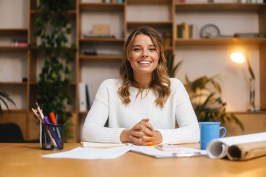 Ofis masasında otururken belgelerle çalışan genç ve güzel bir girişimci kadın.
