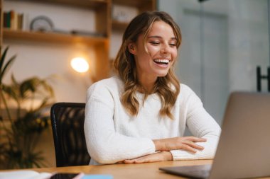Ofis masasında otururken dizüstü bilgisayarla yapılan bir video görüşmesinde genç ve güzel bir kadın yönetici.