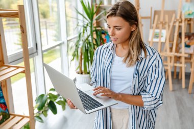 Stüdyo ofis atölyesinde çalışan çekici, kendine güvenen genç bir kadın tasarımcı.