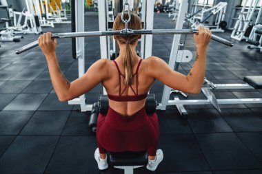 Beyaz tenli sporcu kadın spor salonunda spor yaparken spor malzemeleriyle egzersiz yapıyor.