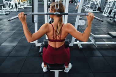 Beyaz tenli sporcu kadın spor salonunda spor yaparken spor malzemeleriyle egzersiz yapıyor.