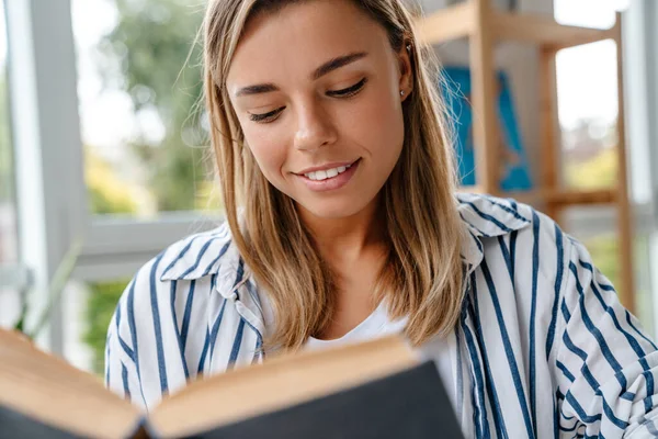 Usmívající Atraktivní Mladá Žena Návrhářka Čtení Knihy Zatímco Sedí Dílně — Stock fotografie