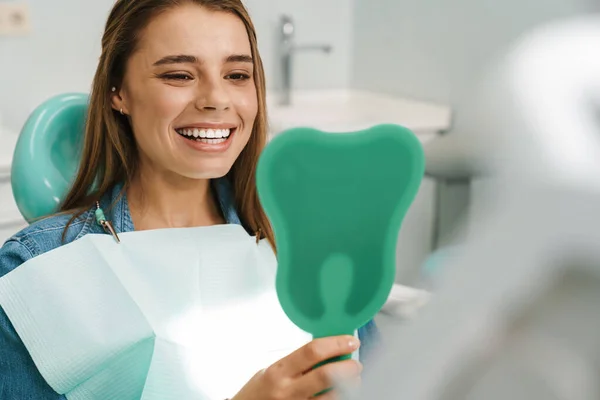 Jovem Mulher Europeia Sorrindo Enquanto Olha Para Espelho Clínica Dentária — Fotografia de Stock