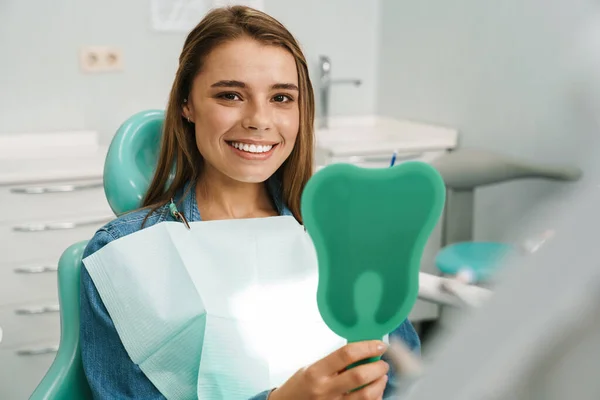 Jovem Mulher Europeia Sorrindo Enquanto Olha Para Espelho Clínica Dentária — Fotografia de Stock