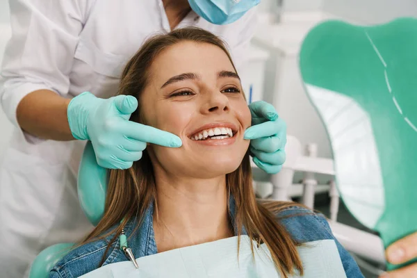 Jovem Mulher Europeia Sorrindo Enquanto Olha Para Espelho Clínica Dentária — Fotografia de Stock