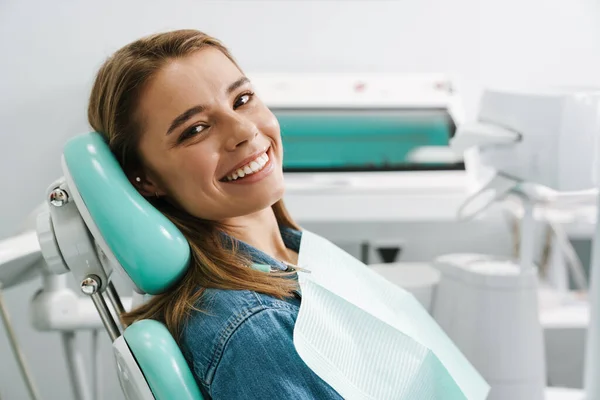 欧洲年轻女子坐在牙科诊所的医疗椅上笑着 — 图库照片