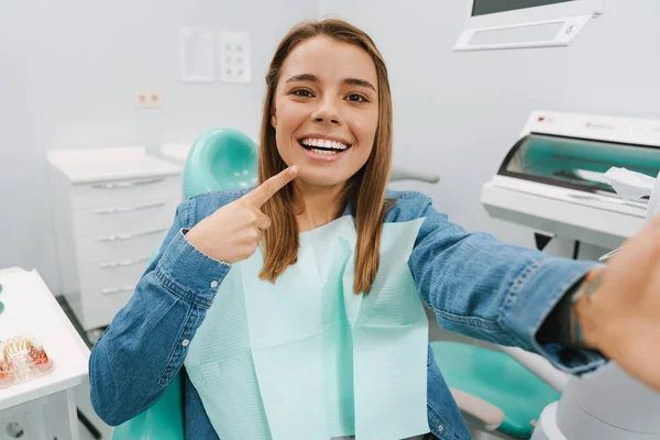 Mulher Alegre Apontando Dedo Para Sorriso Enquanto Toma Selfie Clínica — Fotografia de Stock