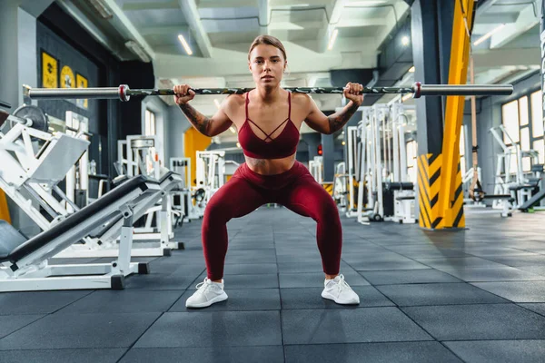 以运动女运动员为重点 在健身房锻炼时用杠铃进行运动 — 图库照片