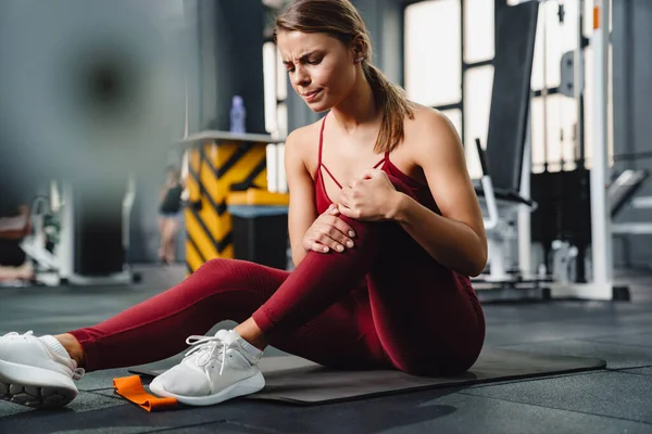 Bild Einer Konzentrierten Unzufriedenen Jungen Fitnesstrainerin Mit Schmerzen Bein Fitnessstudio — Stockfoto