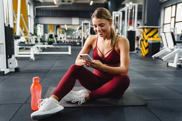 Photo Cheery Positive Young Woman Fitness Coach Using Mobile Phone — Stock Photo, Image