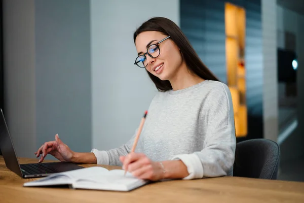 Glad Ung Kvinna Skriva Ner Anteckningar Medan Arbetar Med Bärbar — Stockfoto