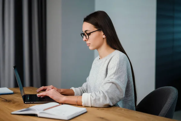 ブルネットは若い女性に焦点を当て眼鏡で作業ノートパソコンとともに自宅 — ストック写真