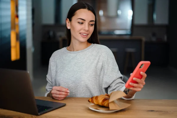 Boldog Fiatal Használja Mobiltelefon Miközben Dolgozik Laptop Otthon — Stock Fotó