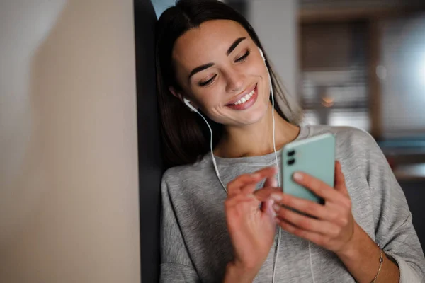 Sorrindo Jovem Ouvindo Música Com Fones Ouvido Telefone Celular Casa — Fotografia de Stock