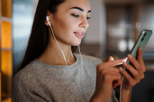 Focused Young Woman Listening Music Earphones Mobile Phone Home — 图库照片