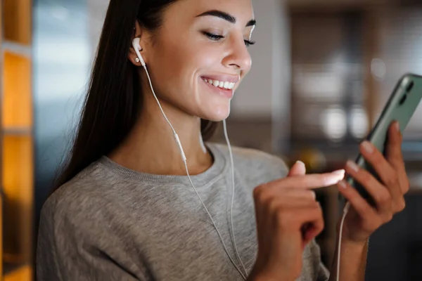 Joyful Young Woman Earphones Smiling While Using Cellphone Home — 图库照片