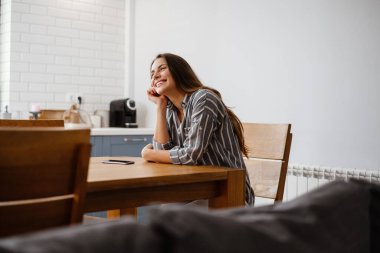 Mutlu, güzel bir kadın evde otururken gülümsüyor.