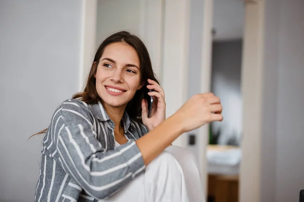 Glückliche Schöne Frau Lächelt Und Telefoniert Während Sie Hause Sitzt — Stockfoto