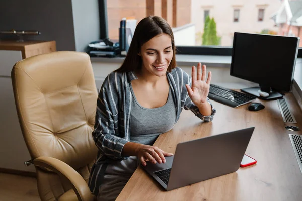 Encantadora Mulher Feliz Acenando Mão Enquanto Trabalhava Com Laptop Casa — Fotografia de Stock