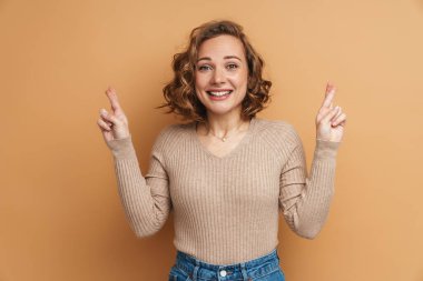 Zencefilli kadın gülümsüyor ve şans diliyor. Bej arka planda izole edilmiş.