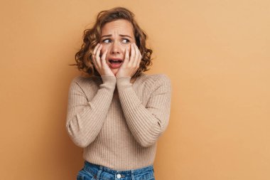 Genç kızıldan korkan kadın bej arka planda izole edilmiş kameraya bakıp bağırıyor.