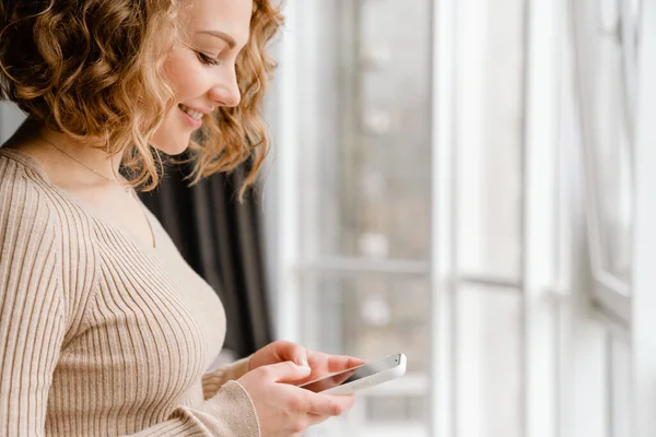 Young Blonde Woman Smiling While Using Mobile Phone Home — Stock Photo, Image