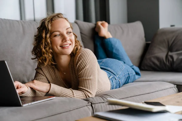 Joven Mujer Blanca Sonriendo Utilizando Ordenador Portátil Mientras Está Acostado — Foto de Stock