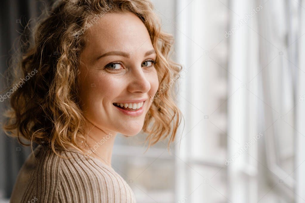 Young blonde woman smiling and looking at camera indoors