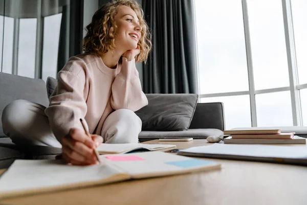 Joven Mujer Blanca Sonriendo Anotando Notas Mientras Está Sentada Sofá — Foto de Stock