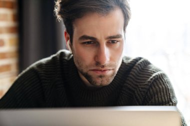 Ciddi orta yaşlı bir adam laptopta evden çalışıyor, kapat.