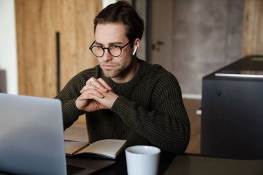 Ciddi orta yaşlı bir adam laptopla evden çalışıyor, düşünüyor.