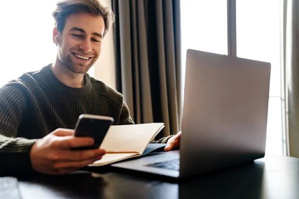 Smiling Mid Aged Man Working Laptop Computer Home Holding Mobile — Stock Photo, Image