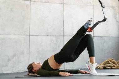 Protezli genç sporcu kadın içeride çalışırken egzersiz yapıyor.