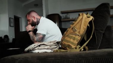 A side view of a disabled military man is sitting on the sofa at home