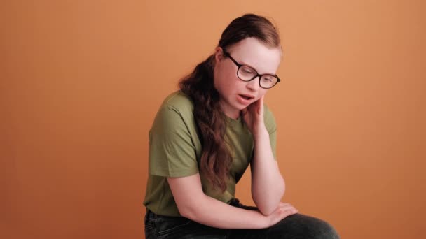 Attractive Girl Syndrome Sitting Talking Camera Isolated Orange Wall Studio — Stock Video