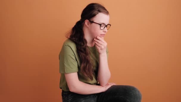 Young Girl Syndrome Sitting Looking Side Isolated Orange Wall Studio — Stok video
