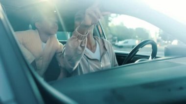 Mutlu bir Afrikalı Amerikalı kadın kızıyla arabada oturuyor.