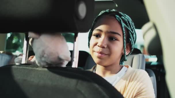 車の中で座っている間 かなり素敵なアフリカ系アメリカ人の女の子のクローズアップビューが彼女のおもちゃで遊んでいます — ストック動画