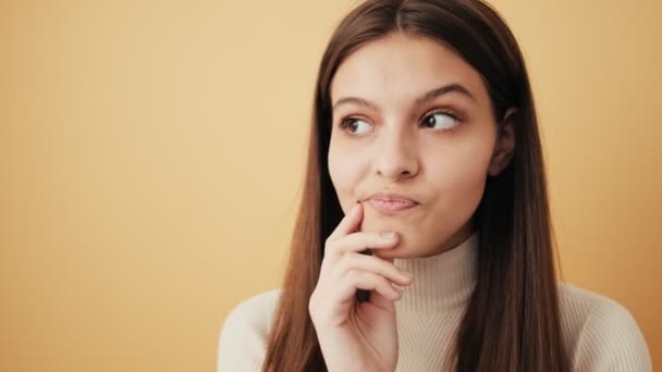 Förvirrad Kvinna Tänker Något Som Står Isolerat Över Beige Vägg — Stockvideo